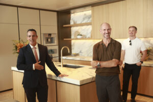 Several people standing in a recently completed kitchen interior.